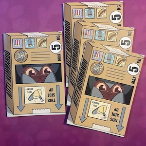 K&ouml;nnte beinhalten: Mehrere Pappkartons mit dem Text "KITTY KOMMANDO" und Illustrationen eines Katzenkopfes. Jede Box hat eine Gewichtsbeschr&auml;nkung von 5 kg. Die Boxen zeigen auch Essenssymbole und den Text "THIS SIDE UP".