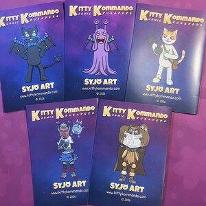 K&ouml;nnte beinhalten: F&uuml;nf Comic-Hefte mit dem Titel "Kitty Kommando" mit Cartoon-Charakteren auf den Covern. Die Cover sind lila mit gelbem und wei&szlig;em Text. Der Name des K&uuml;nstlers und die Website sind unten auf jedem Comic abgedruckt.