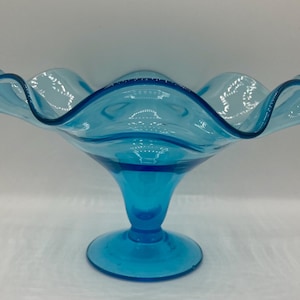 May include: A blue glass bowl with a ruffled edge and a pedestal base.