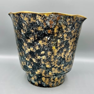 May include: A black ceramic planter with a gold speckled glaze and a scalloped rim.