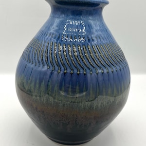 May include: A blue and green ceramic vase with a textured surface. The vase has a wide base and a narrow neck.