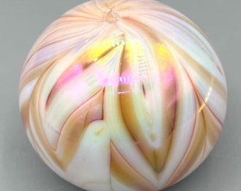May include: A white glass paperweight with swirling patterns of pink, orange, and gold.