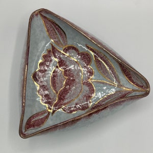 May include: A triangular ceramic dish with a floral design. The dish is white with a pink and gold floral pattern.