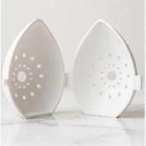 May include: Two white, teardrop-shaped, microwave egg cookers, open to reveal the interior. Each half has a series of small, circular holes arranged in a spiral pattern. The cookers are designed to cook eggs in the microwave.