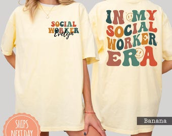May include: A pale yellow t-shirt featuring a small chest graphic that reads Social Worker Evelyn and a large back graphic with the text In My Social Worker Era in a retro, multi-colored font with small star and smiley face accents.