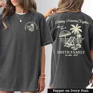 a gray t-shirt with a graphic design on the back, depicting a beach scene with a palm tree, beach chair, and umbrella. The design includes text that reads "Making Memories Together" and "Smith Family Vacation Miami Beach".