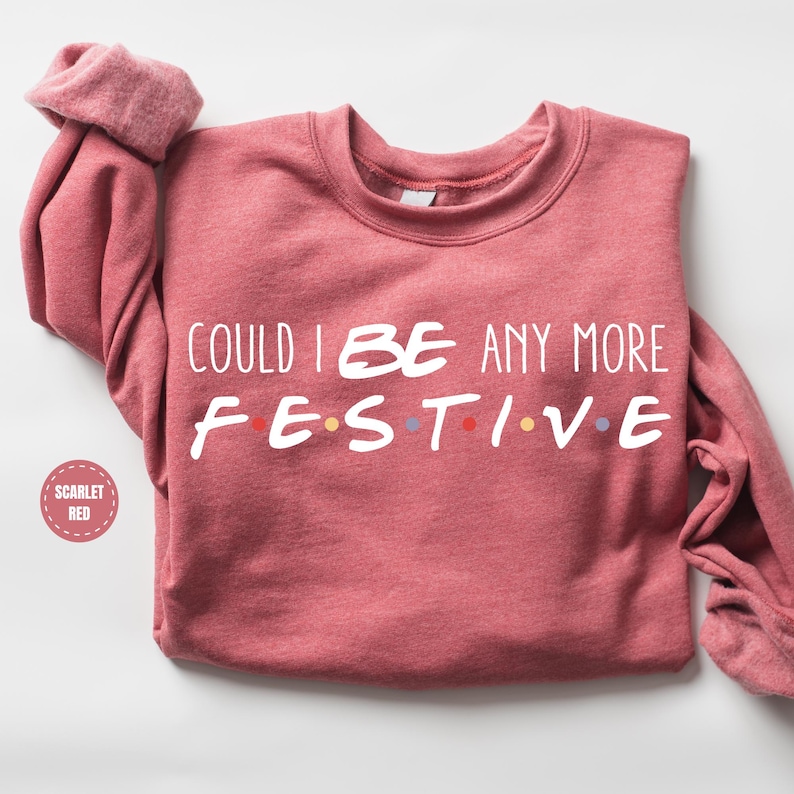 A red sweater with the text "COULD I BE ANY MORE FESTIVE" printed on it.