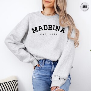 a woman wearing a grey sweatshirt with the word madam on it