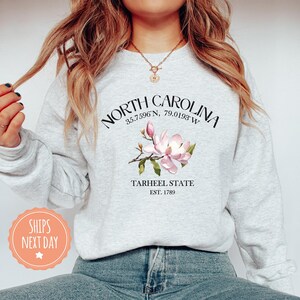 a woman wearing a north carolina sweatshirt and jeans
