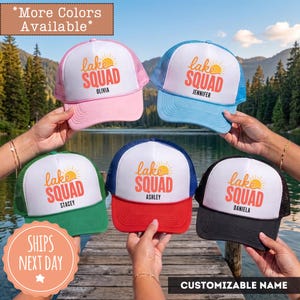 May include: Five trucker hats with white front panels and colored brims and mesh backs. Each hat features a graphic of a sun and the text "lake SQUAD" in orange, with a unique name printed in black below the text on each individual hat.