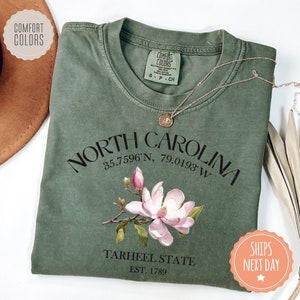 a green shirt with a pink flower on it