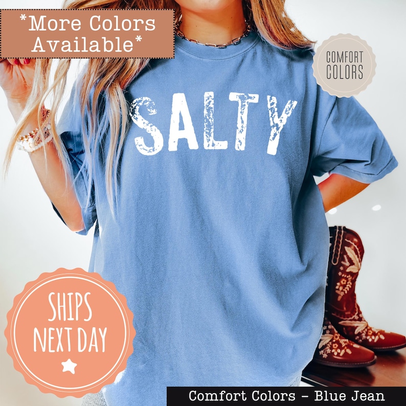 A woman wearing a blue t-shirt with the word "SALTY" printed on it, standing next to a pair of red cowboy boots.