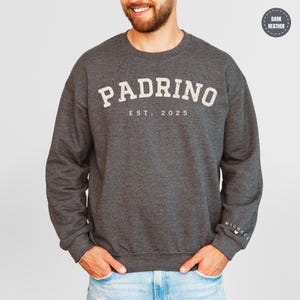 A man wearing a gray sweatshirt with the word "PADRINO" printed on it.