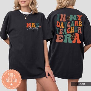 a woman wearing a black t - shirt with the words in my care teacher era