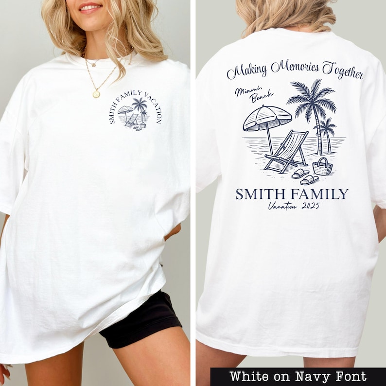 A white t-shirt with a graphic design on the back, featuring a beach scene with a palm tree, beach chair, and umbrella.
