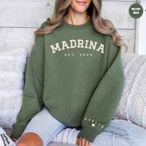 a woman sitting on a couch wearing a green sweatshirt