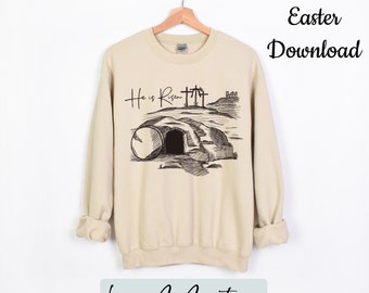 May include: A beige sweatshirt with a black graphic of a tomb with a stone rolled away and the text "He is Risen" above it. The graphic also includes a cross with the words "He is Risen" above it.