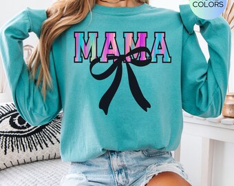 May include: A turquoise blue long-sleeved sweatshirt with the word "MAMA" printed in rainbow colors with a black bow underneath. The sweatshirt is made by Comfort Colors.