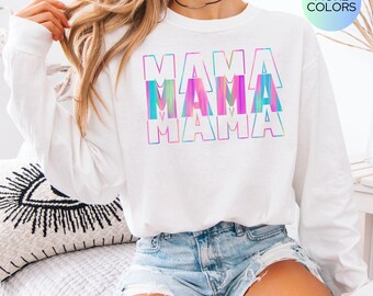 May include: White long-sleeve sweatshirt with the word "MAMA" repeated three times in a rainbow ombre design. The sweatshirt is being worn by a person.