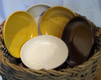 May include: Four ceramic bowls in a wicker basket. The bowls are in various colors, including yellow, brown, white, and speckled brown.