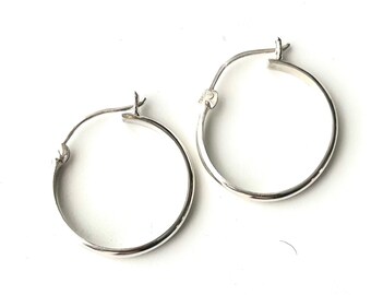 May include: A pair of silver hoop earrings. The earrings are simple and classic, with a smooth, polished finish.