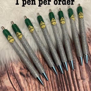 May include: Eight silver glitter pens with green and yellow labels that say "Oxygen 2". The text "1 pen per order" is at the top of the image.