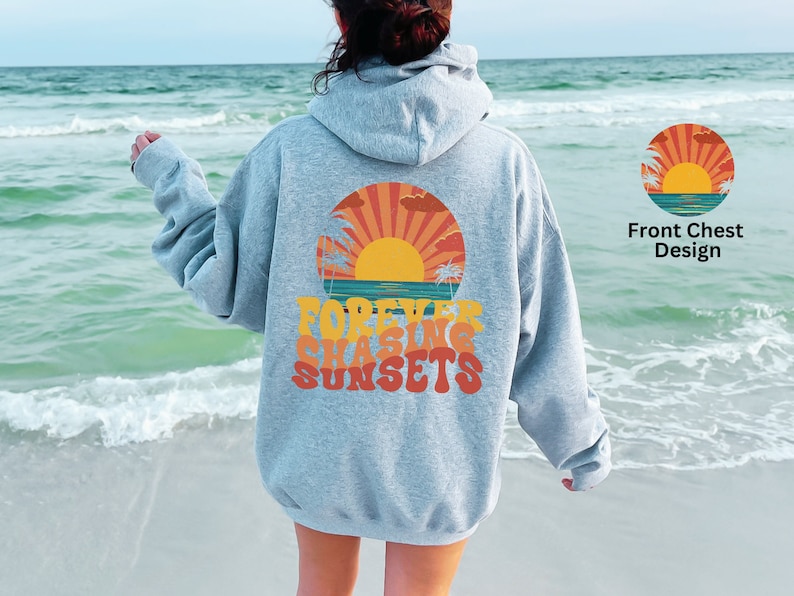 Puede incluir: Una sudadera con capucha gris claro con un gr&aacute;fico de puesta de sol retro y el texto "FOREVER CHASING SUNSETS" impreso en la espalda. La parte delantera de la sudadera con capucha presenta una versi&oacute;n m&aacute;s peque&ntilde;a del gr&aacute;fico de la puesta de sol.