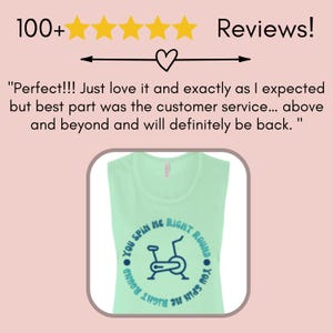 May include: A light green sleeveless shirt with the text "You Spin Me Right Round" encircling a blue graphic of a stationary exercise bike. The shirt has a rounded neckline.