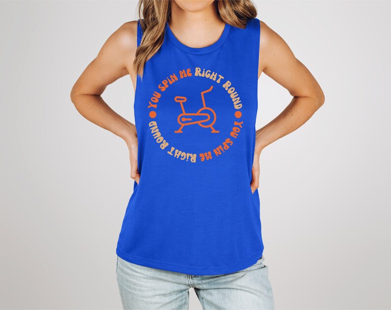 May include: A sleeveless blue tank top with the text "YOU SPIN ME RIGHT ROUND" encircling an orange illustration of a stationary exercise bike. The text and graphic are centered on the front of the top.