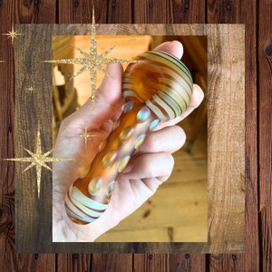 May include: A glass pipe with a brown, white, and blue swirl design. The pipe has a rounded bowl and a long, thin stem.