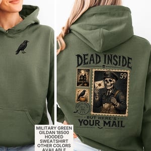 May include: A military green hooded sweatshirt featuring a small black crow graphic on the front chest. The back displays a large graphic of a skeleton mail carrier with the text DEAD INSIDE BUT HERE'S YOUR MAIL and postage stamp illustrations.