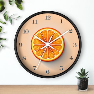 Op de afbeelding: Een ronde oranje klok met zwarte cijfers en wijzers. De wijzerplaat van de klok is licht oranje van kleur met een grote oranje schijf in het midden. De cijfers 1 tot en met 12 zijn in het zwart gedrukt rond de rand van de wijzerplaat.