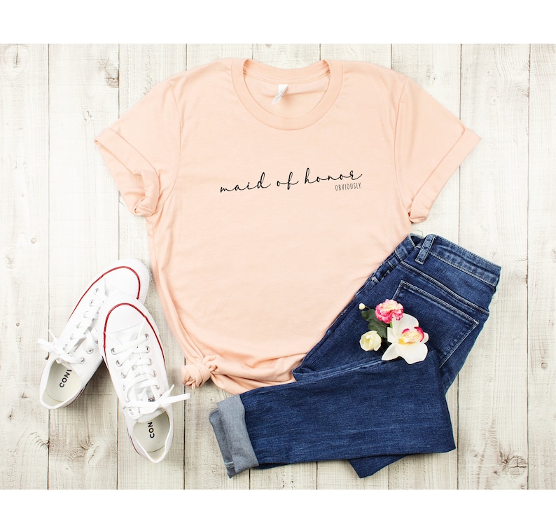 May include: Peach coloured t-shirt with the text "maid of honour" and "obviously" in black script.