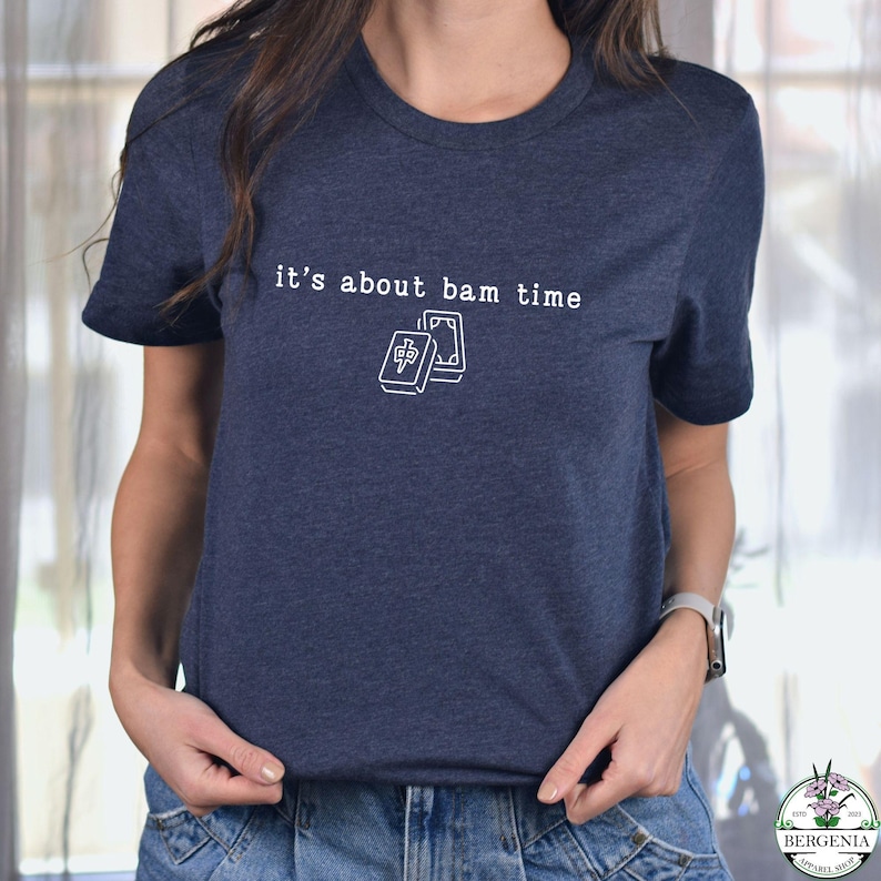 Puede incluir: Camiseta azul marino con el texto "it's about bam time" y un gr&aacute;fico blanco de dos fichas de Mahjong. La camiseta es de cuello redondo y tiene mangas cortas.