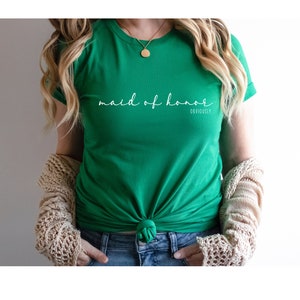 May include: A green t-shirt with the text "maid of honour obviously" in white script.