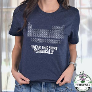 May include: Navy blue t-shirt featuring a periodic table design in white. The shirt includes the text "I WEAR THIS SHIRT PERIODICALLY". The shirt is from Bergenia Apparel Shop.