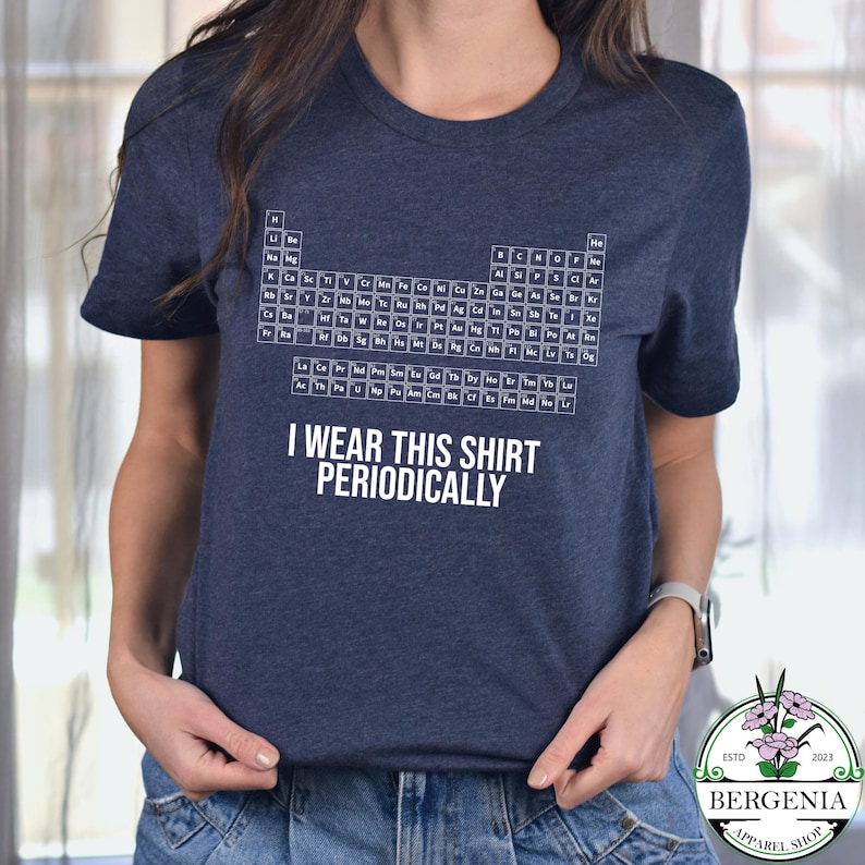 May include: Navy blue t-shirt featuring a periodic table design in white. The shirt includes the text "I WEAR THIS SHIRT PERIODICALLY". The shirt is from Bergenia Apparel Shop.