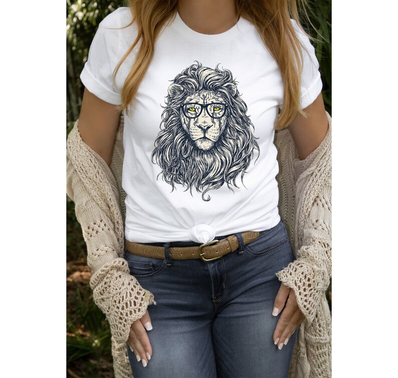 以下が含まれることがあります： 眼鏡をかけたライオンのグラフィックがプリントされた白いTシャツ。ライオンは長いたてがみと真剣な表情をしています。