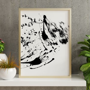 May include: Abstract art print in a gold frame. The artwork features black ink splatters and brushstrokes on a white background. A flock of birds flies across the top. The overall theme is modern and minimalist.