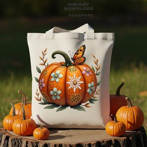 Peut inclure: Un sac fourre-tout crème avec un motif de citrouille. La citrouille orange est ornée de fleurs bleues et roses, d'un flocon de neige et d'un papillon. De petites citrouilles entourent le sac sur une surface en bois.