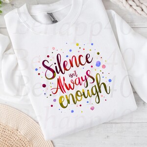 Peut inclure: Sweat-shirt blanc avec l'inscription "Silence isn't Always enough" dans un design coloré de style aquarelle. Le texte est entouré de points colorés. Le sweat-shirt est en matière souple.