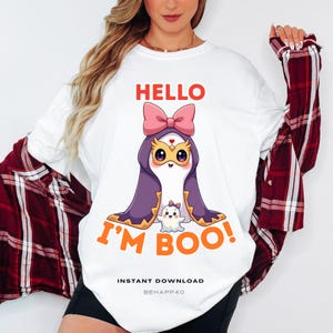 Peut inclure: T-shirt blanc avec un motif sur le thème d'Halloween. Le motif présente un personnage de dessin animé avec une cape violette, un nœud rose et le texte "HELLO I'M BOO!" en orange et rouge. Le texte "INSTANT DOWNLOAD" est imprimé en dessous.