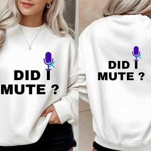 Peut inclure: Sweat-shirt blanc avec l'inscription "DID I MUTE ?" en noir et un motif de microphone violet barré d'un "X" bleu. Le sweat-shirt est présenté de face et de dos.