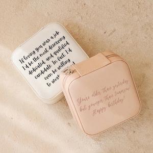 May include: Two small square jewelry boxes with zipper closures. The white box has the text "If loving you was a job. I'd be the most deserving. dedicated and qualified candidate. In fact. I'd even be willing to work" printed on it. The pink box has the text "You're older than yesterday but younger than tomorrow! Happy birthday!!" printed on it.