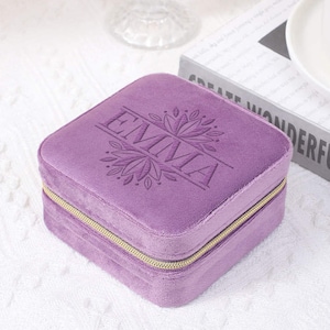 May include: A purple velvet jewelry box with a gold zipper and the name "EMMA" embroidered on the top.