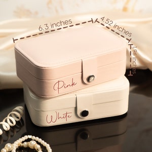 May include: Two jewelry boxes, one pink and one white, stacked on top of each other. The pink box is 6.3 inches long, 4.52 inches wide, and 1.96 inches tall. The pink box has the word "Pink" written on it. The white box has the word "White" written on it.