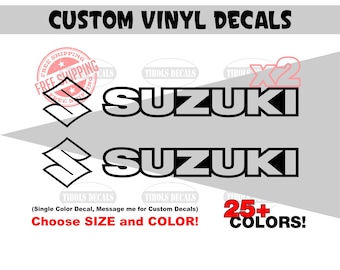 May include: Two black and grey Suzuki vinyl decals featuring the brand logo and text. The image includes the text CUSTOM VINYL DECALS, X2, and 25+ COLORS. The decals are displayed against a light grey background with additional text elements.