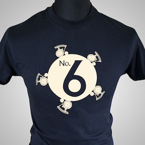 May include: A navy blue t-shirt with a white circle design featuring the number "6" and the text "No." surrounded by stylized bicycle wheels.