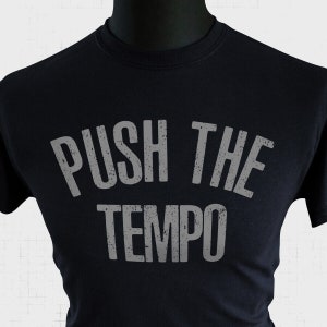 Op de afbeelding: Zwart T-shirt met een witte, verweerde grafische afbeelding met de tekst "PUSH THE TEMPO".