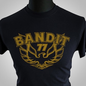 May include: Black t-shirt with a gold graphic of a phoenix with the text "Bandit 77" above it.